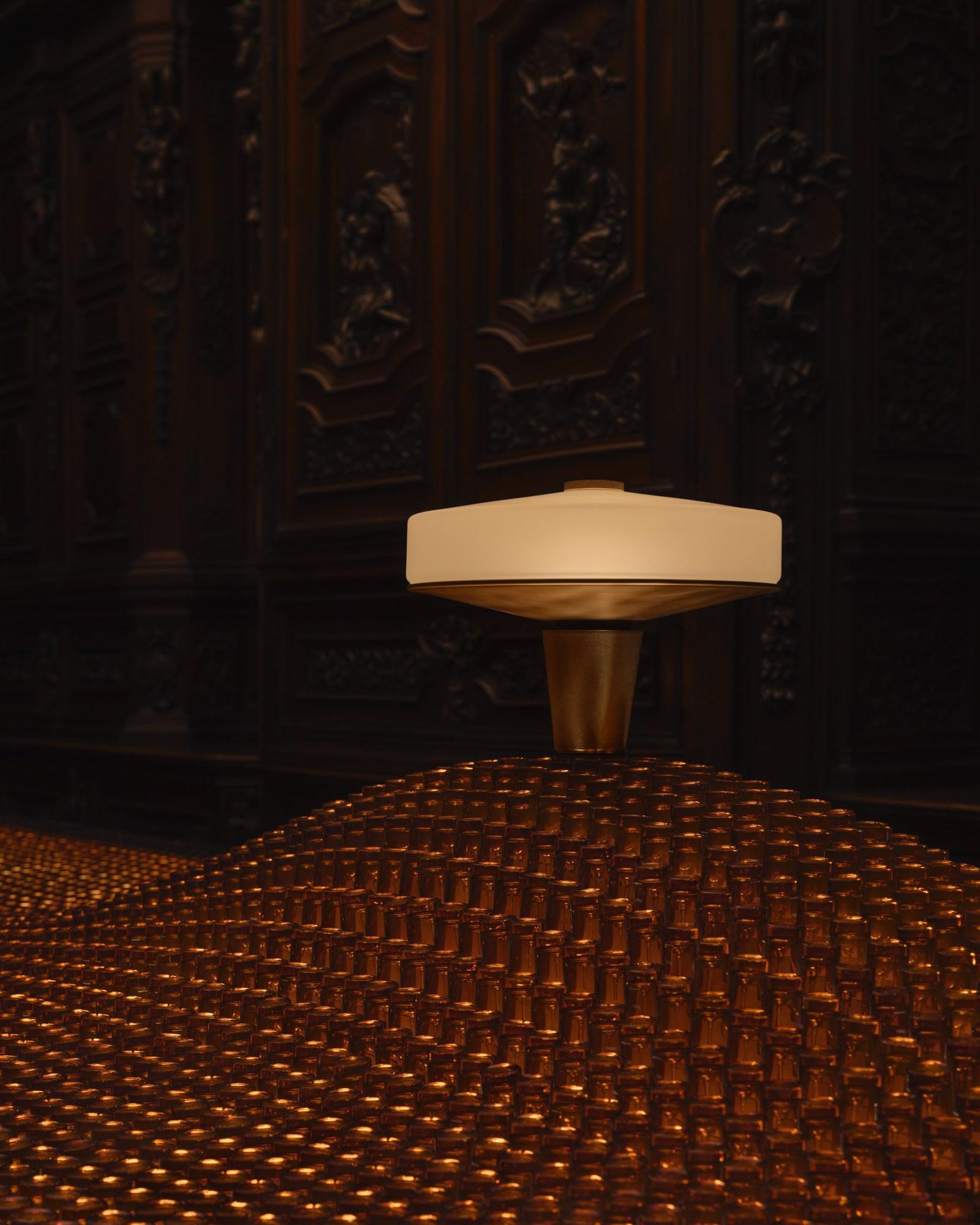 Aesop Apose lamp with hand-cast brass plinth and Murano-style glass crown, Factory of Light installation Milan 2026