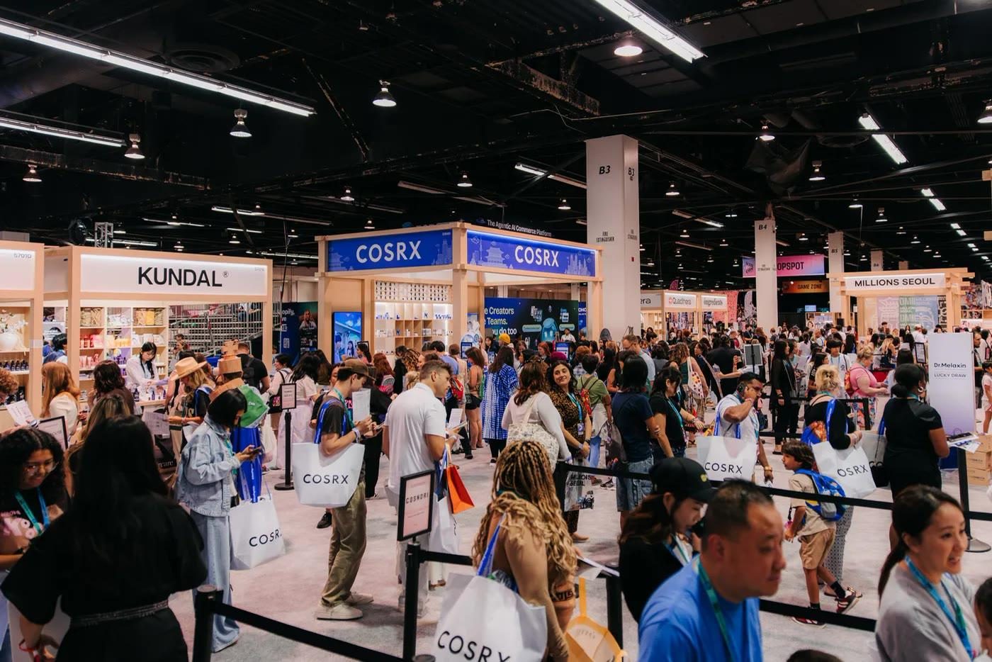 The K-beauty rows: continuous, camera-ready backdrops aisle after aisle, VidCon 2026 expo floor, Anaheim